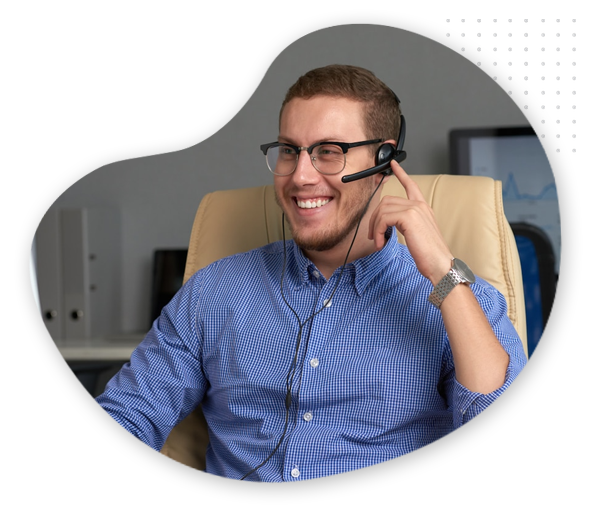 Blog-marketing-img A smiling man wearing glasses and a headset sits in an office chair, appearing engaged in a conversation, possibly offering tech support or discussing Blog Marketing strategies with a client.