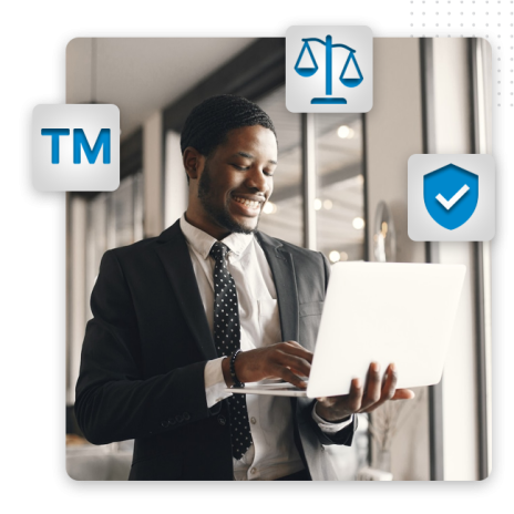 A smiling man in a suit uses a laptop in a bright office. Trademark, justice scales, and shield icons appear around him, symbolizing legal protection and professional logo design for intellectual property concepts.